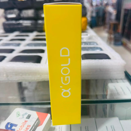 A bright yellow rectangular product box standing upright on a glass display counter, with the brand name 'ΑΩΡ' printed vertically in white. The background is a blurred retail store environment with shelves and items.