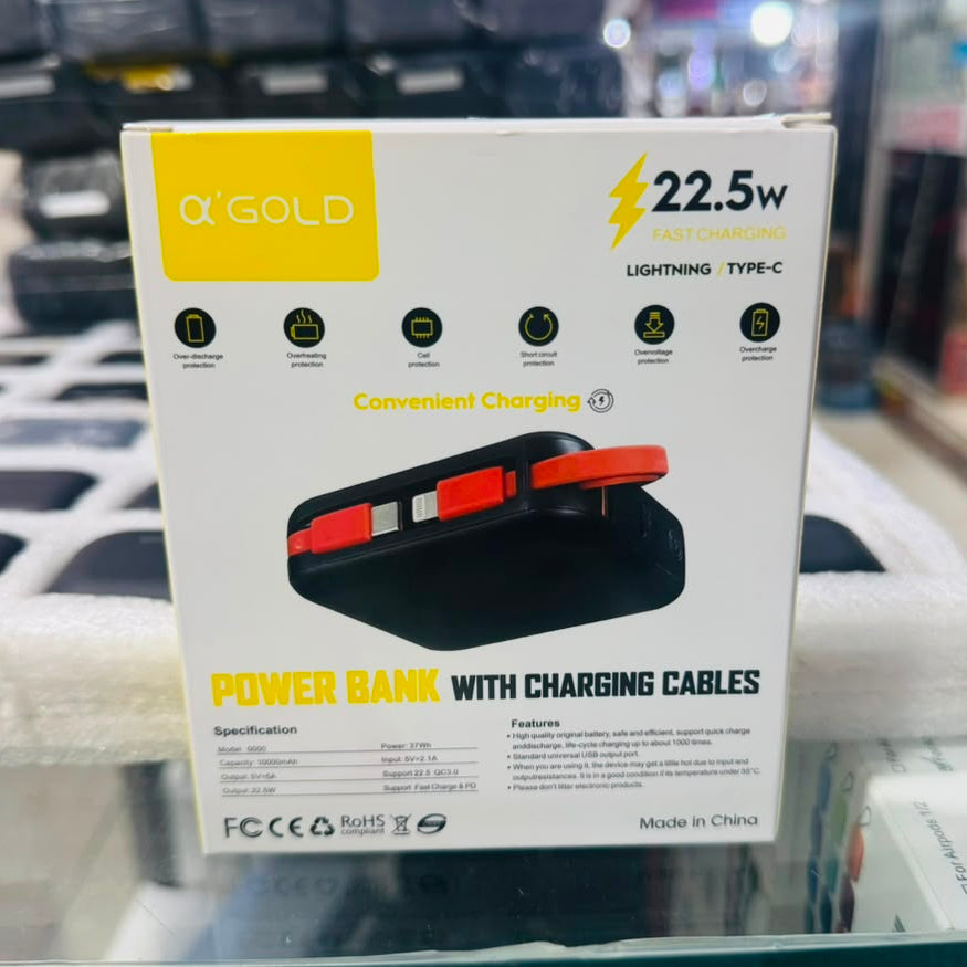 A boxed Q'Gold power bank with charging cables, shown in retail packaging on a glass display shelf. The box is white with yellow and black text and graphics, including '22.